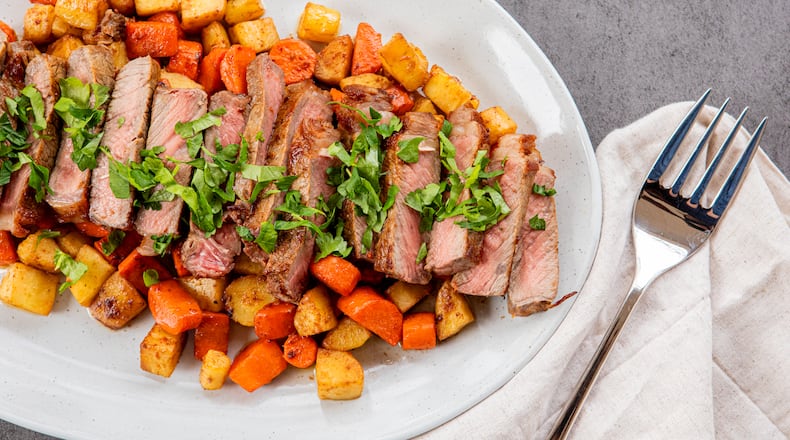 New York Strip Steaks with Root Vegetables and Herb Butter. (Aaliyah Man for The Atlanta Journal-Constitution)