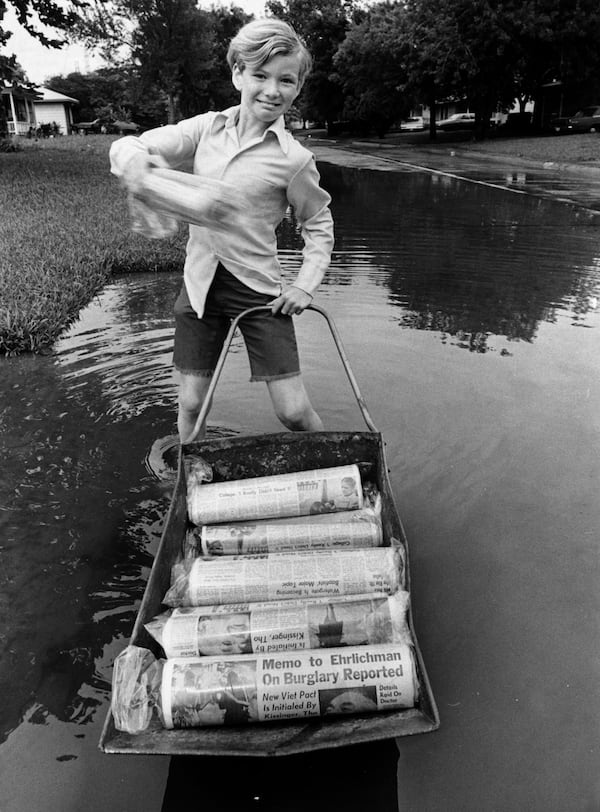 FILE - Gary Magness, 10, Chronicle carrier and a third-grader at Red Bluff Elementary School in Pasadena, delivers his papers on a floating wheelbarrow that skims over high water left by torrential rains. (Greg Smith/Houston Chronicle via AP)