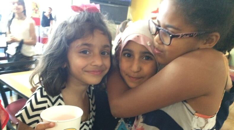 The author's daughter Celia, right, hugs her classmate, who is returning to Iraq for the summer, alongside a student who arrived new this year and adapted quickly.