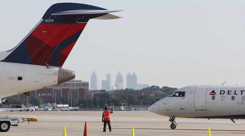 A Delta Air Lines ground crew member guides an aircraft on the tarmac on August 8, 2019, at Hartsfield-Jackson International Airport in Atlanta. (Bob Andres / robert.andres@ajc.com)