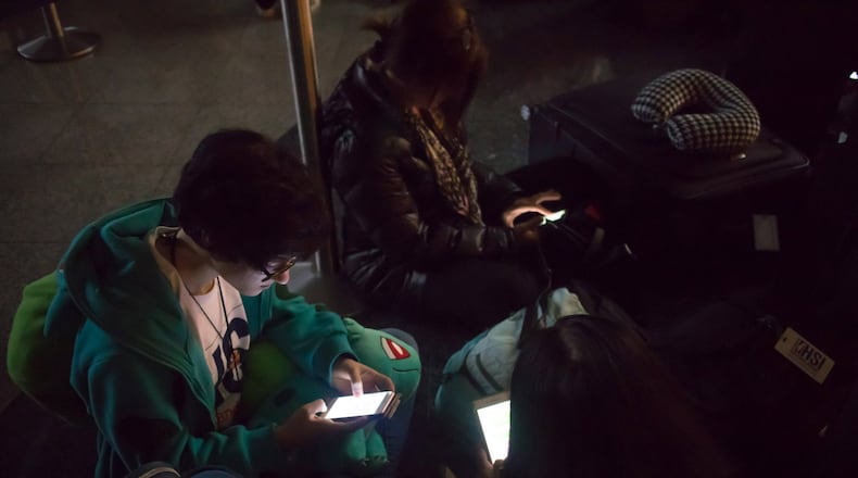 Isabelle Jacobs waits for her flight to New York in a dark terminal at Hartsfield-Jackson International Airport Sunday, December 17, 2017. The Airport is reporting a loss of electricity. The FlightAware site reports the airport is currently holding all inbound flights due to an equipment outage. STEVE SCHAEFER / SPECIAL TO THE AJC