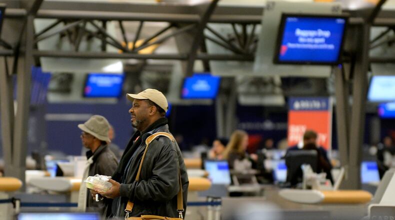 Passengers walk through a nearly deserted ticketing area after Delta Air Lines cancelled 573 flights and Southwest Airlines suspended most operations into and out of Hartsfield-Jackson International Airport in advance of an ice storm on Tuesday, Feb. 11, 2014 in Atlanta. The city dodged the first punch of a dangerous winter storm Tuesday, but forecasters warned of a potentially "catastrophic" second blow in a thick layer of ice that threatened to bring hundreds of thousands of power outages and leave people in their cold, dark homes for days. (AP Photo/David Tulis)