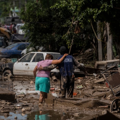 FILE - A Navy officer helps a woman cross a flooded street after heavy rain in Poza Rica, Veracruz state, Mexico, Oct. 12, 2025. (AP Photo/Felix Marquez, File)