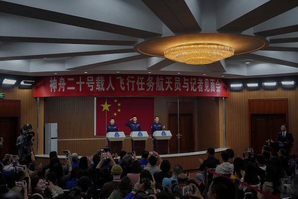 Astronaut for the upcoming Shenzhou 20 mission Chen Dong, center, salutes next to his comrades Wang Jie, left, and Chen Zhongrui during a meeting with the press at the Jiuquan Satellite Launch Center in northwest China, Wednesday, April 23, 2025. (AP Photo/Andy Wong)
