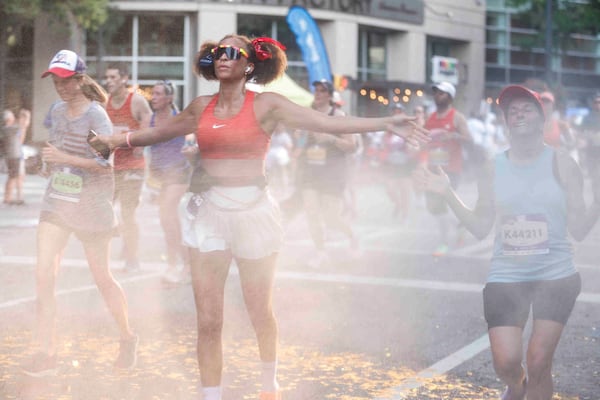 Runners run through a stream of water during the last mile of the 2025 AJC Peachtree Road Race on Friday, July 4, 2025. (Natrice Miller/ AJC)