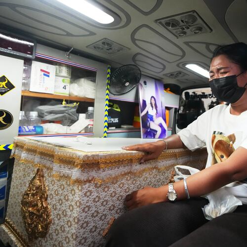 A relative of a victim in a music bar fire sits near the coffin containing the victim's body inside a vehicle as it is transferred from a police hospital in Bangkok, Thailand, Wednesday, July 15, 2026, (AP Photo/Sakchai Lalit)