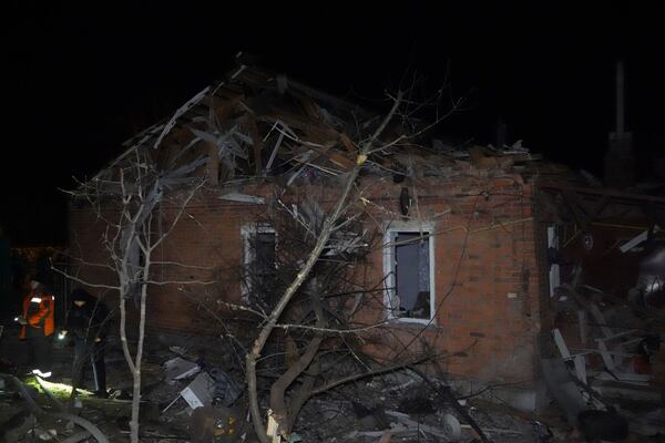People stand near a house destroyed in a Russian strike on a residential neighborhood of Kharkiv, Ukraine, Saturday, March 29, 2025. (AP Photo/Andrii Marienko)