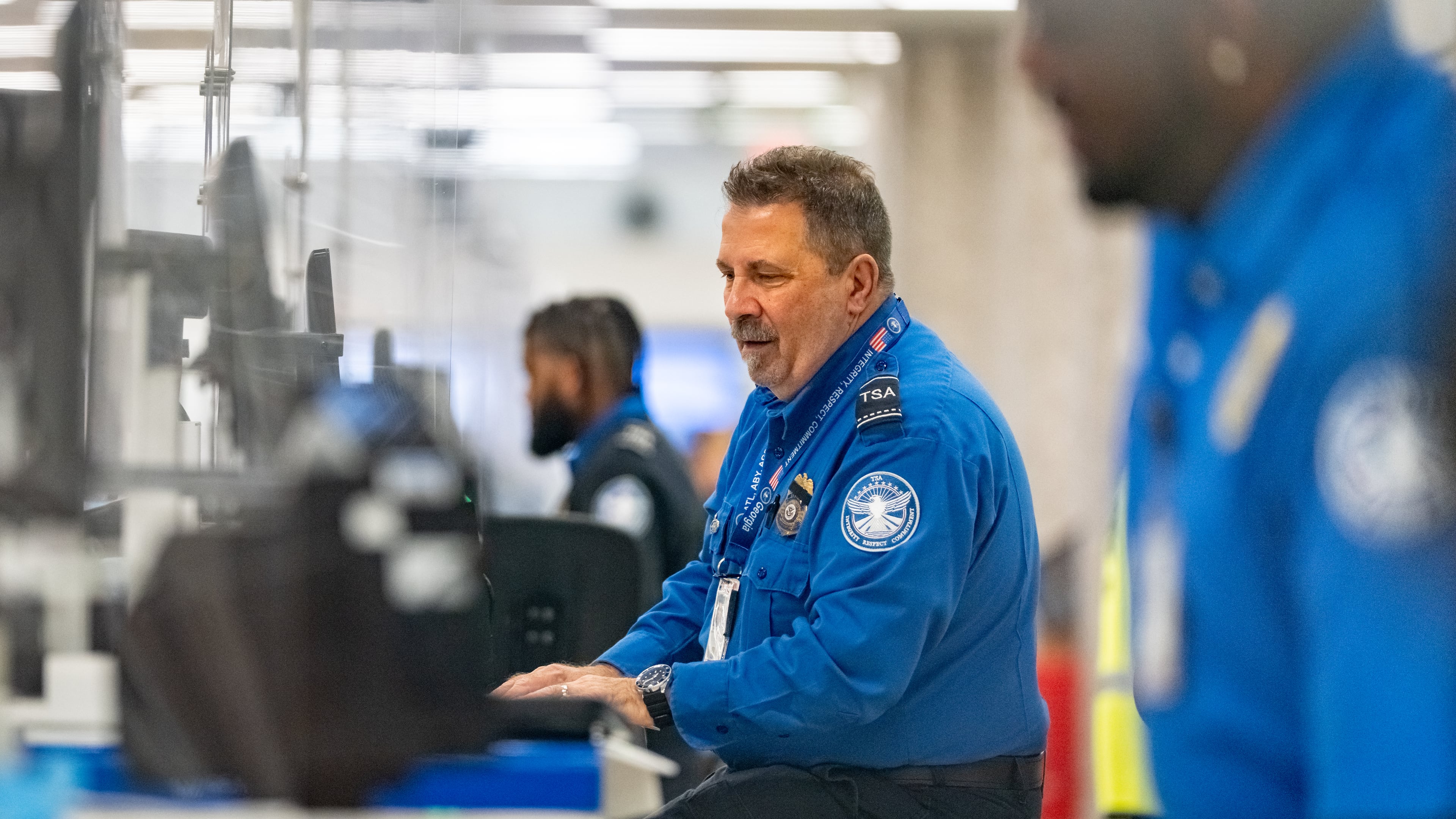A Transportation Security Administration officer checks the identification of travelers at Hartsfield-Jackson Atlanta International Airport on Wednesday, Oct. 1, 2025. Air traffic controllers and TSA screeners who are deemed essential are continuing to work through the shutdown. (Ben Hendren for the AJC)