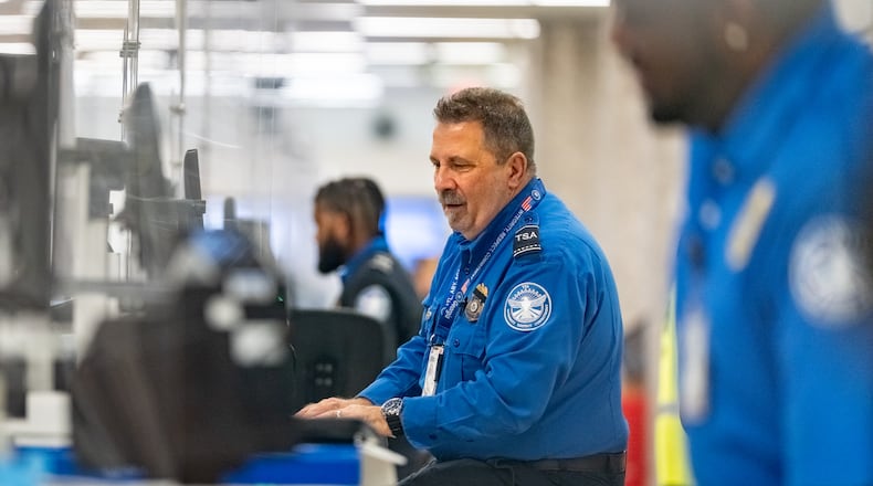 A Transportation Security Administration officer checks the identification of travelers at Hartsfield-Jackson Atlanta International Airport on Wednesday, Oct. 1, 2025. Air traffic controllers and TSA screeners who are deemed essential are continuing to work through the shutdown. (Ben Hendren for the AJC)