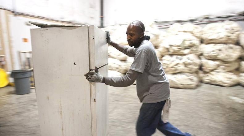 A man pushes a fridge into an appliance recycling center in this file photo.