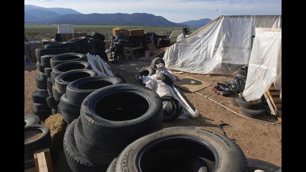 FILE - In this Aug. 10, 2018, file photo, is a makeshift living compound in Amalia, N.M. Prosecutors seeking to keep two men and three women jailed on child-abuse charges in northern New Mexico now say they seized a document entitled "Phases of a Terrorist Attack" at the filthy desert compound where 11 children and a dead boy were found. In a court filing Friday, Aug. 24, 2018, prosecutors said the hand-written document had instructions for "The one-time terrorist" and mentioned an unnamed place called "the ideal attack site." (AP Photo/Morgan Lee, File)