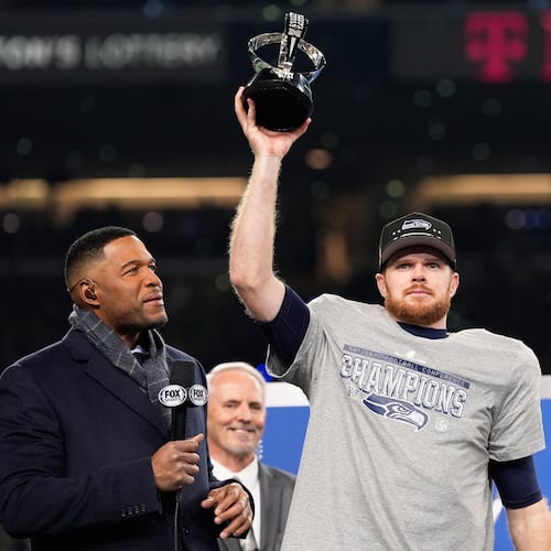 Seattle Seahawks quarterback Sam Darnold lifts the winner's trophy next to Michael Strahan, left, after a win over the Los Angeles Rams in the NFC Championship NFL football game Sunday, Jan. 25, 2026, in Seattle. (AP Photo/Godofredo A. Vásquez)
