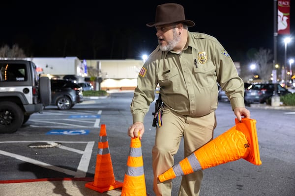 Kevin Kelley, operations manager for the Tara Theatre, sets up cones for fans lining up to see the “Stranger Things” series finale on Wednesday, Dec. 31, 2025. He also happened to be dressed as Hopper (David Harbour) with the khaki sheriff’s outfit and Mountie-style hat. (Arvin Temkar/AJC)