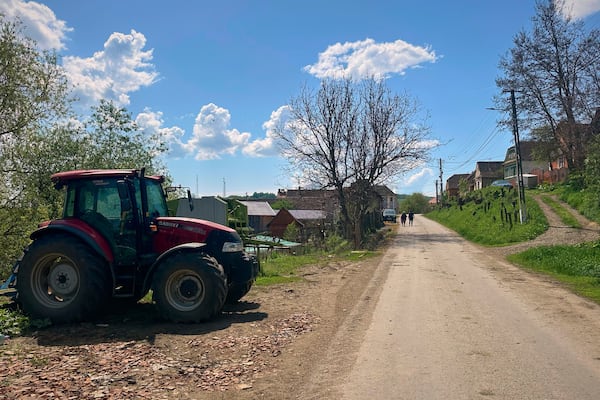 People walk on a road in the village of Saschiz, in Romania's central Transylvania region, Friday, April 25, 2025. (AP Photo/Stephen McGrath)