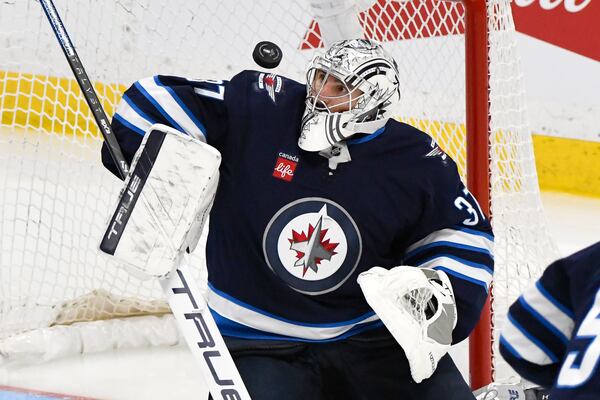 Winnipeg Jets goaltender Connor Hellebuyck (37) makes a save against a St. Louis Blues shot during the third period of Game 2 of a first-round NHL hockey playoff series in Winnipeg, Manitoba, Monday April 21, 2025. (Fred Greenslade/The Canadian Press via AP)
