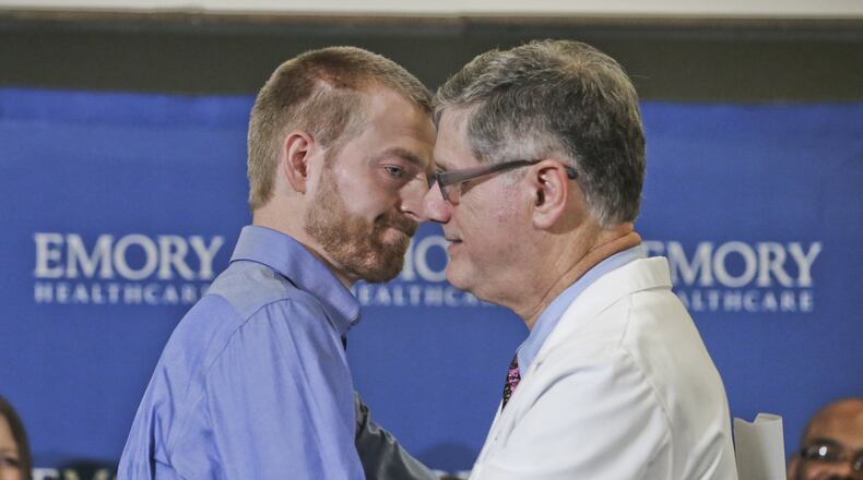 Aug. 21: Dr. Kent Brantly (left) embraces Director of Emory’s Infectious Diseases Unit, Dr. Bruce Ribner, after he made a statement at Emory University Hospital annex following his discharge. JOHN SPINK/JSPINK@AJC.COM