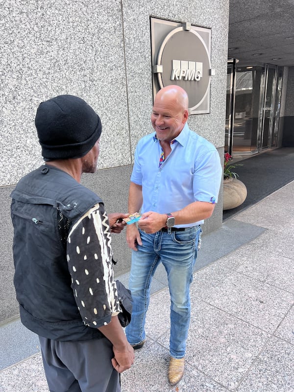 Street Charity co-founder John Patton hands a Street Charity a $5 prepaid gift card to an unhoused resident in need of food. (Courtesy of Street Charity)