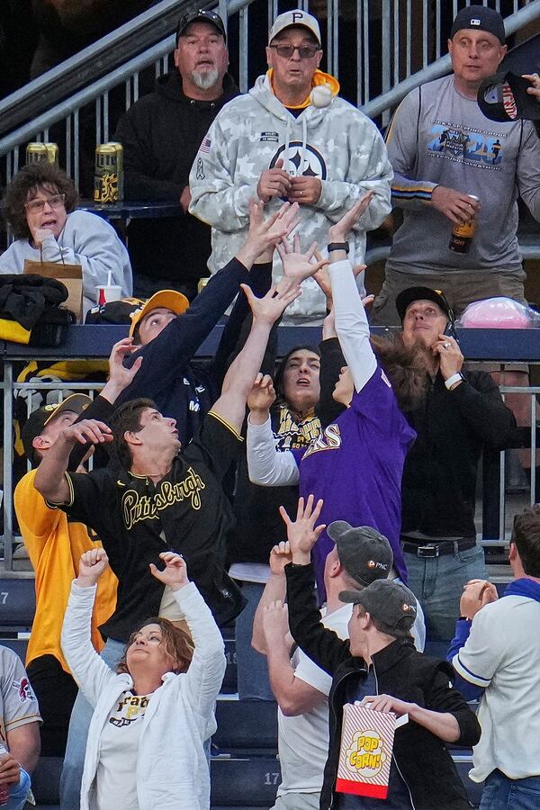 Fans reach for the ball hit by Pittsburgh Pirates' Jared Triolo for a solo home run off Atlanta Braves pitcher Bryce Elder during the sixth inning of a baseball game in Pittsburgh, Friday, May 9, 2025. (AP Photo/Gene J. Puskar)