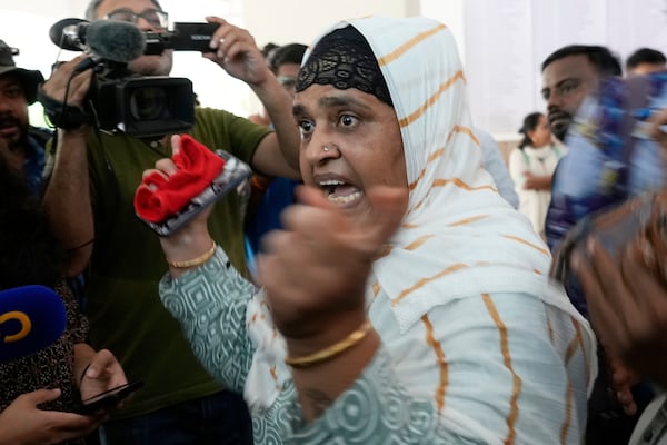 Salma Rafiq Memon, in white scarf, gestures angrily as she speaks to media personnel while waiting for the bodies of four relatives who died in the Air India plane crash, at a hospital in Ahmedabad, India, Saturday, June 14, 2025. (AP Photo/Rafiq Maqbool)