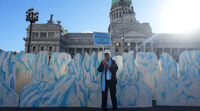 A demonstrator holds a banner that reads in Spanish, "The homeland is not for sale, it's defended" as lawmakers debate the Javier Milei government's proposal to reform the glacier protection law, outside Congress in Buenos Aires, Argentina, Wednesday, April 8, 2026. (AP Photo/Rodrigo Abd)