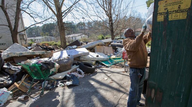 In this photo from February 2016, resident James Starr, who had lived at Brennon Hill for four years, puts his trash in a Dumpster despite trash and debris everywhere on the property. The site was later condemned and now the demolition will be complete. AJC file photo
