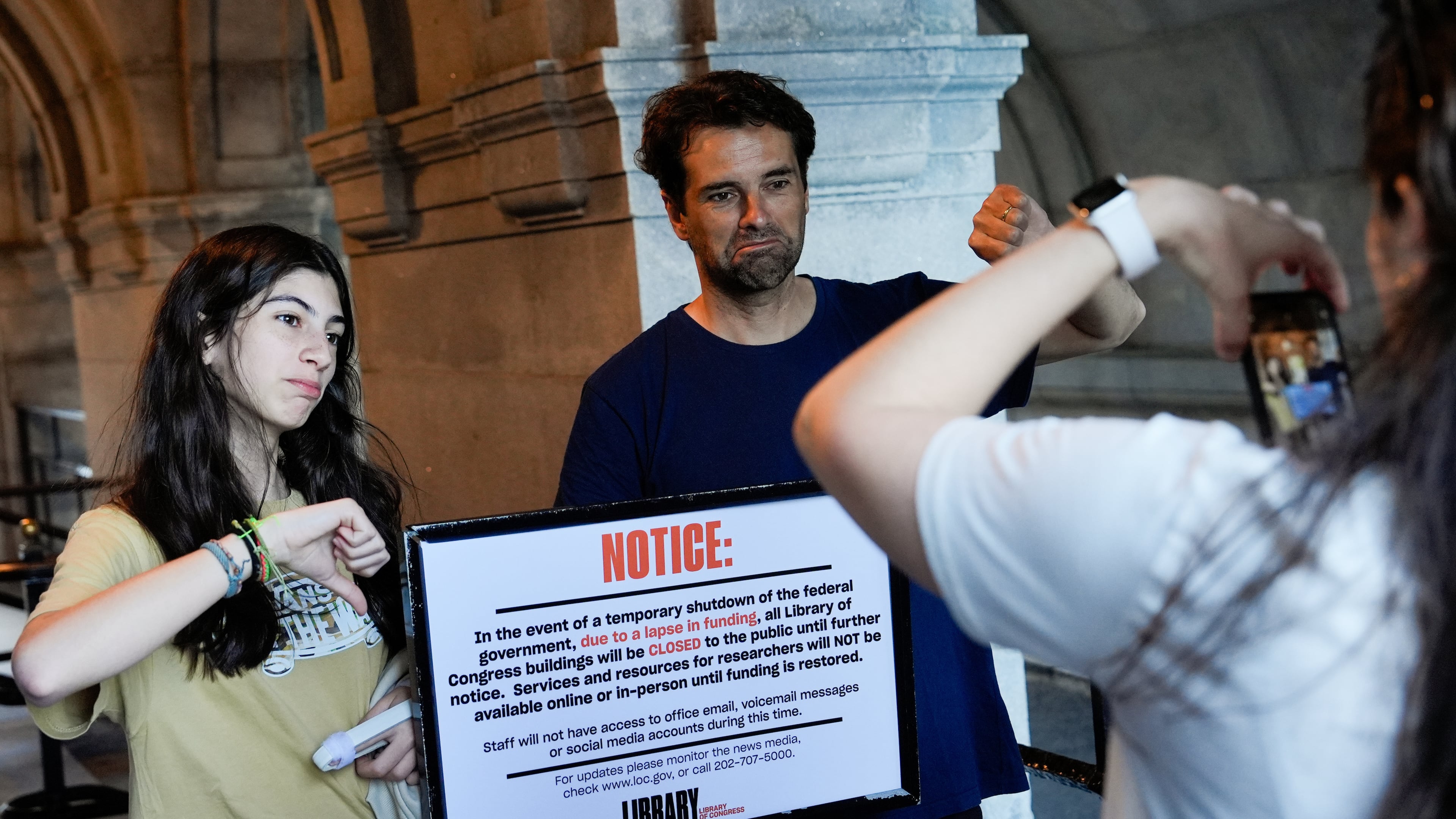 People take photos with a sign announcing that the Library of Congress is closed, on the first day of a partial government shutdown, Wednesday, Oct. 1, 2025, in Washington. (AP Photo/Julia Demaree Nikhinson)