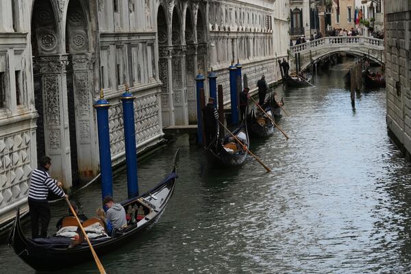 Gondola sail in a canal in Venice, Italy, Friday, April 18, 2025, Venice on Friday launches for a second year a pilot program to charge day-trippers an entrance fee. (AP Photo/Antonio Calanni)