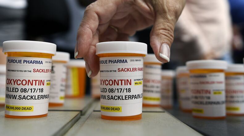 In this Aug. 17, 2018, photo, family and friends who have lost loved ones to OxyContin and other opioid overdoses leave pill bottles in protest outside the headquarters of Purdue Pharma. (AP Photo/Jessica Hill)