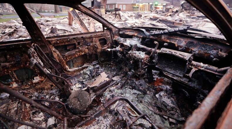 A burned car sits in a parking lot Wednesday, Nov. 30, 2016, in Gatlinburg, Tenn., after a wildfire swept through the area Monday. Three more bodies were found in the ruins of wildfires that torched hundreds of homes and businesses in the Great Smoky Mountains area, officials said Wednesday. (AP Photo/Mark Humphrey)