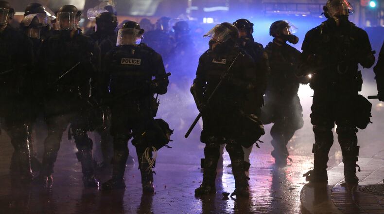 CORRECTS TO SOUTHWEST YAMHILL Police deploy a chemical irritant and flash bang grenades at the intersection of Southwest Yamhill and 5th Avenue as a crowd marches through the streets of Portland, Ore., following Donald Trump's presidential inauguration, Friday, Jan. 20, 2017. Authorities said some people in the crowd - that at one point numbered in the thousands - threw rocks, bottles, flares and "unknown liquid" at officers Friday night. The city's entertainment district was closed following the rowdy gathering. (Dave Killen/The Oregonian via AP)