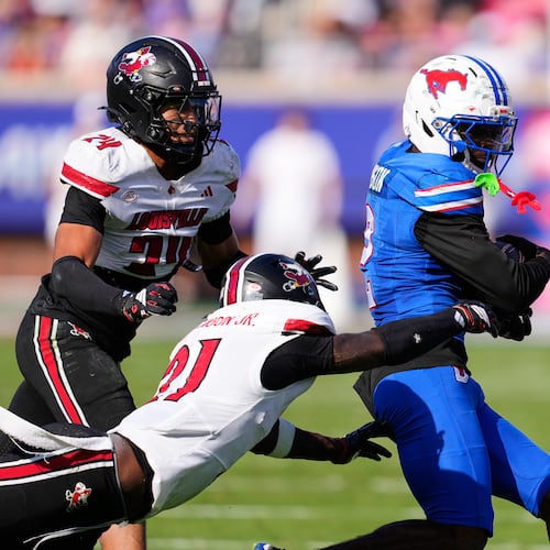 SMU wide receiver Jordan Hudson (2) catches a pass and is tackled by Louisville defensive back D'Angelo Hutchinson (21) and defensive back Corey Gordon (24) in the second half of an NCAA college football game Saturday, Nov. 22, 2025, in Dallas. (AP Photo/Tony Gutierrez)
