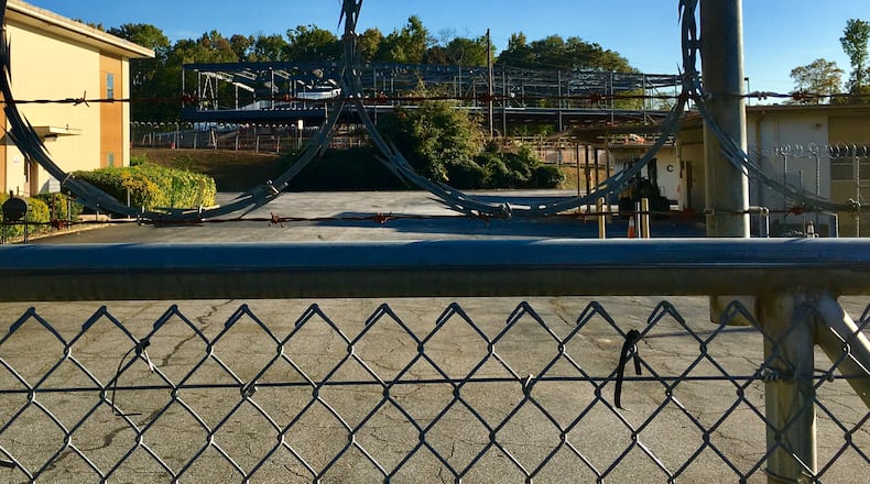 The abandoned AT&T property in east Decatur as seen through barbed wire with steel beams of the new Talley St. school rising in the background. The city has long envisioned a park and retention pond for the site, but is still in negotiations with the company. Decatur’s master plan shows extending New Street—from where this photo was taken—straight to Talley Street fronting the school. Bill Banks for the AJC