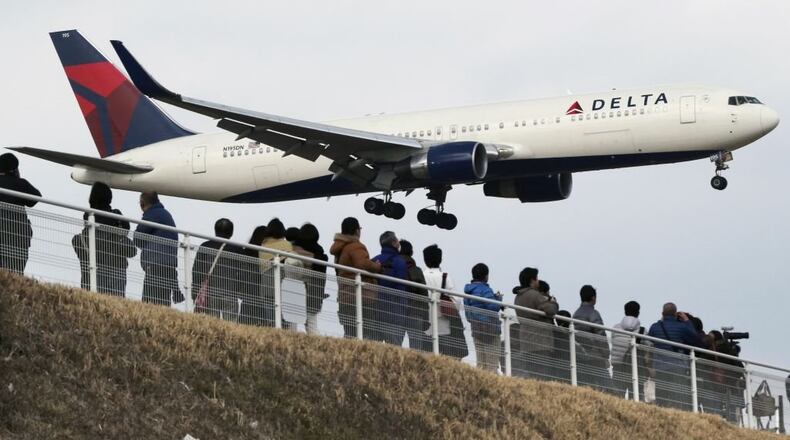 People watch as a Delta Air Lines jet lands at Narita Airport, about an hour east of central Tokyo.