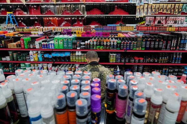 An employee at Seven Daughters, a beauty supply store in College Park, Ga., is surrounded by products as he stocks the shelves, Tuesday, May 6, 2025. (AP Photo/Stephanie Scarbrough)