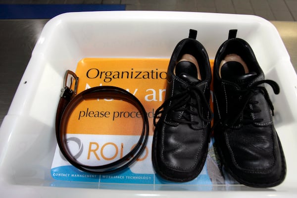 FILE - In this Wednesday, Jan. 10, 2007, file photo, a belt and shoes sit in a trays with advertising that is being used in the safety screening of travelers done by the Transportation Security Administration, at the Los Angeles International Airport in Los Angeles. (AP Photo/Ann Johansson, File)