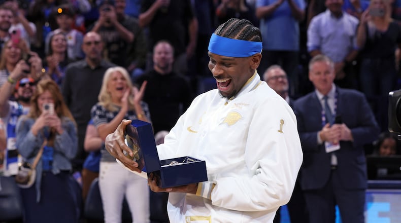 Oklahoma City Thunder guard Shai Gilgeous-Alexander looks at his championship ring during a ceremony before an NBA basketball game against the Houston Rockets Tuesday, Oct. 21, 2025, in Oklahoma City. (AP Photo/Nate Billings)