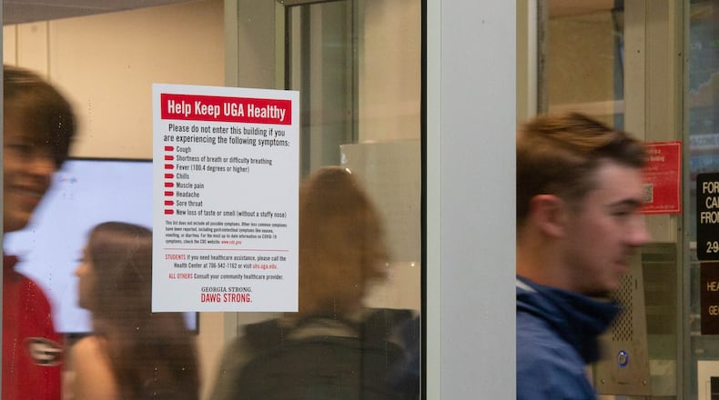 New residents of the Lipscomb dormitory exit the building past a sign advising persons experiencing COVID-19 symptoms not to enter on Monday, Aug. 16, 2021 on the University of Georgia's Campus in Athens, Georgia. The University does not have a mask or vaccine mandate, and is not requiring testing. (Julian Alexander for the Atlanta Journal-Constitution)