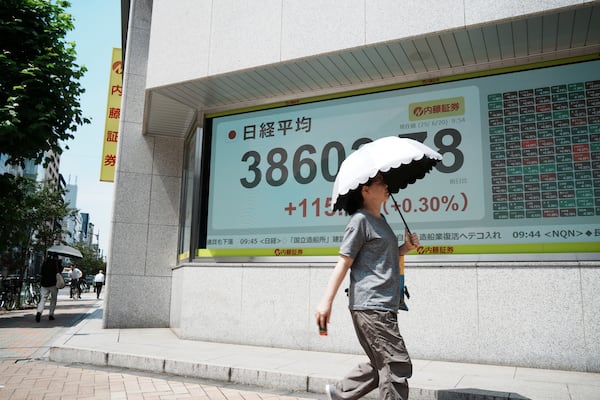 A person walks in front of an electronic stock board showing Japan's Nikkei index at a securities firm Friday, June 20, 2025, in Tokyo. (AP Photo/Eugene Hoshiko)