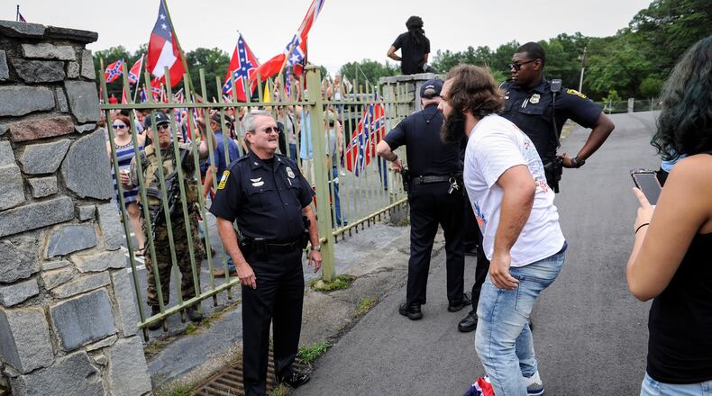 A Stone Mountain police officer separates a man stomping on the Confederate flag from a large group of flag sympathizers rallying at Stone Mountain Park, Aug. 1. (Photo / John Amis)