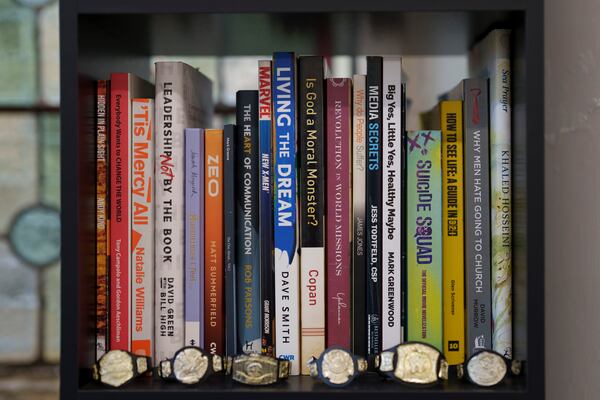 Mini wrestling belts are seen with self-help and religious themed books backstage at St Peter's Church in Shipley before one of Kingdom Wrestling's monthly wrestling shows, Saturday, March 29, 2025. (AP Photo/Jon Super)