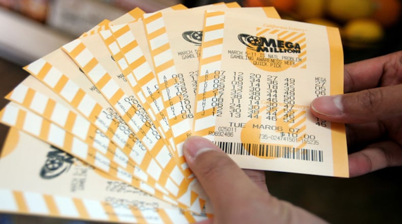 <p>Man holds a bundle of Mega Millions lottery tickets </p>