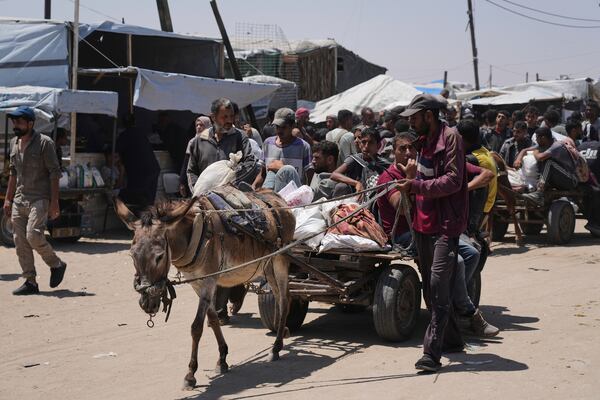 Palestinians carry bags containing food and humanitarian aid packages delivered by the Gaza Humanitarian Foundation, a U.S.-backed organization, in Rafah, southern Gaza Strip, Monday, June 16, 2025. (AP Photo/Abdel Kareem Hana)