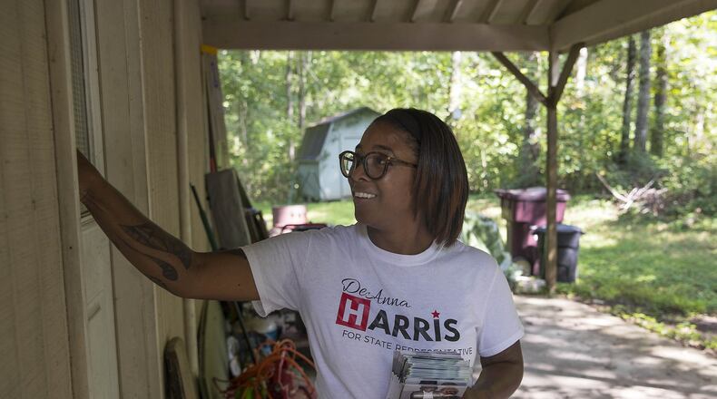 Republican DeAnna Harris places a campaign flyer in the door of a house along Leatherleaf Drive Southwest in Marietta. Harris, who is running for a state House seat in a district where voters favored Hillary Clinton over Donald Trump in the 2016 presidential election, says she tries to focus conversations with voters on what’s happening in the district, not in the White House. “When people come at me with the whole Trump conversation, I have to bring them back,” she said. (ALYSSA POINTER/ALYSSA.POINTER@AJC.COM)