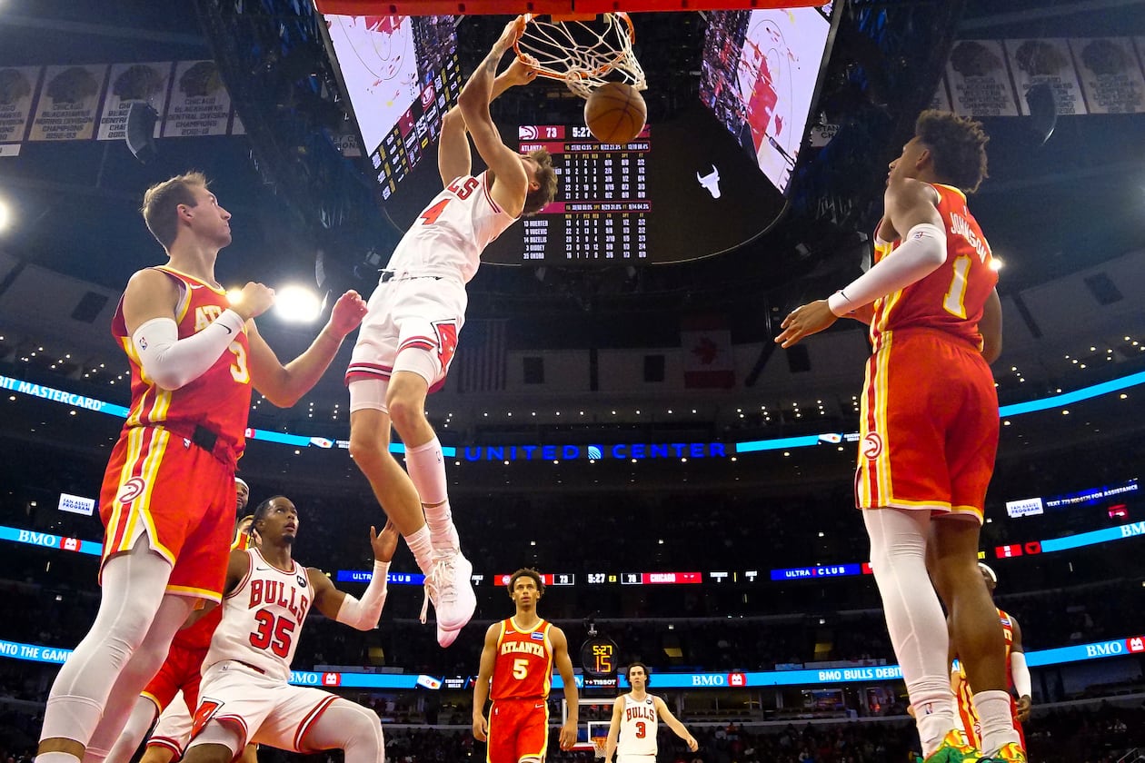 Bulls forward Matas Buzelis (center) dunks the ball on Hawks guard Luke Kennard (left) and forward Jalen Johnson during the second half on Monday, Oct. 27, 2025, in Chicago. (David Banks/AP)