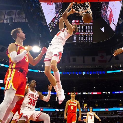 Chicago Bulls forward Matas Buzelis, center, dunks the ball on Atlanta Hawks guard Luke Kennard, left, and forward Jalen Johnson during the second half of an NBA basketball game Monday, Oct. 27, 2025, in Chicago. (AP Photo/David Banks)
