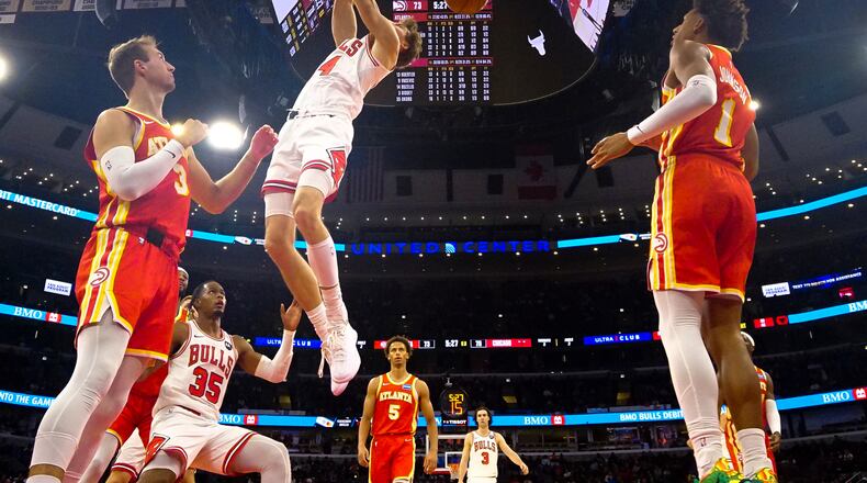 Bulls forward Matas Buzelis (center) dunks the ball on Hawks guard Luke Kennard (left) and forward Jalen Johnson during the second half on Monday, Oct. 27, 2025, in Chicago. (David Banks/AP)