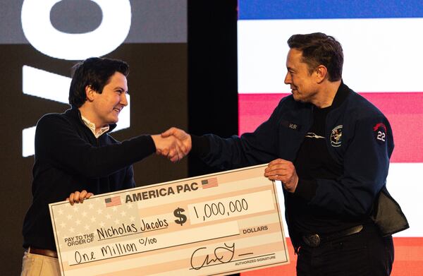 Tech titan Elon Musk (right) hands over a $1 million check during a town hall in Green Bay, Wisconsin, in March 2025. (Jeffrey Phelps/AP)