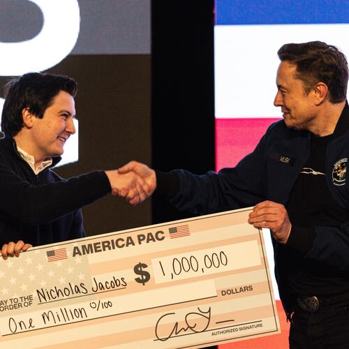 FILE - Elon Musk hands over a million dollar check to Nicholas Jacobs during a town hall in Green Bay, Wis., March 30, 2025. (AP Photo/Jeffrey Phelps, File)