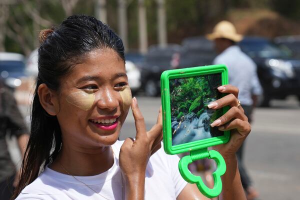 A girl applies Thanakha, traditional make-up, on her face as she takes part in the first day of annual water festival also known as "Thingyan," in Naypyitaw, Myanmar, Sunday, April 13, 2025. (AP Photo/Aung Shine Oo)