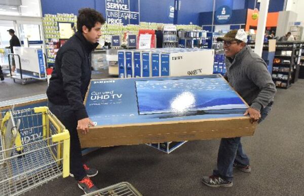 Ramiro Diaz (right) and his son Gabriel Dias load a television onto their cart inside Best Buy in Duluth on Friday, November 25, 2016. HYOSUB SHIN / HSHIN@AJC.COM